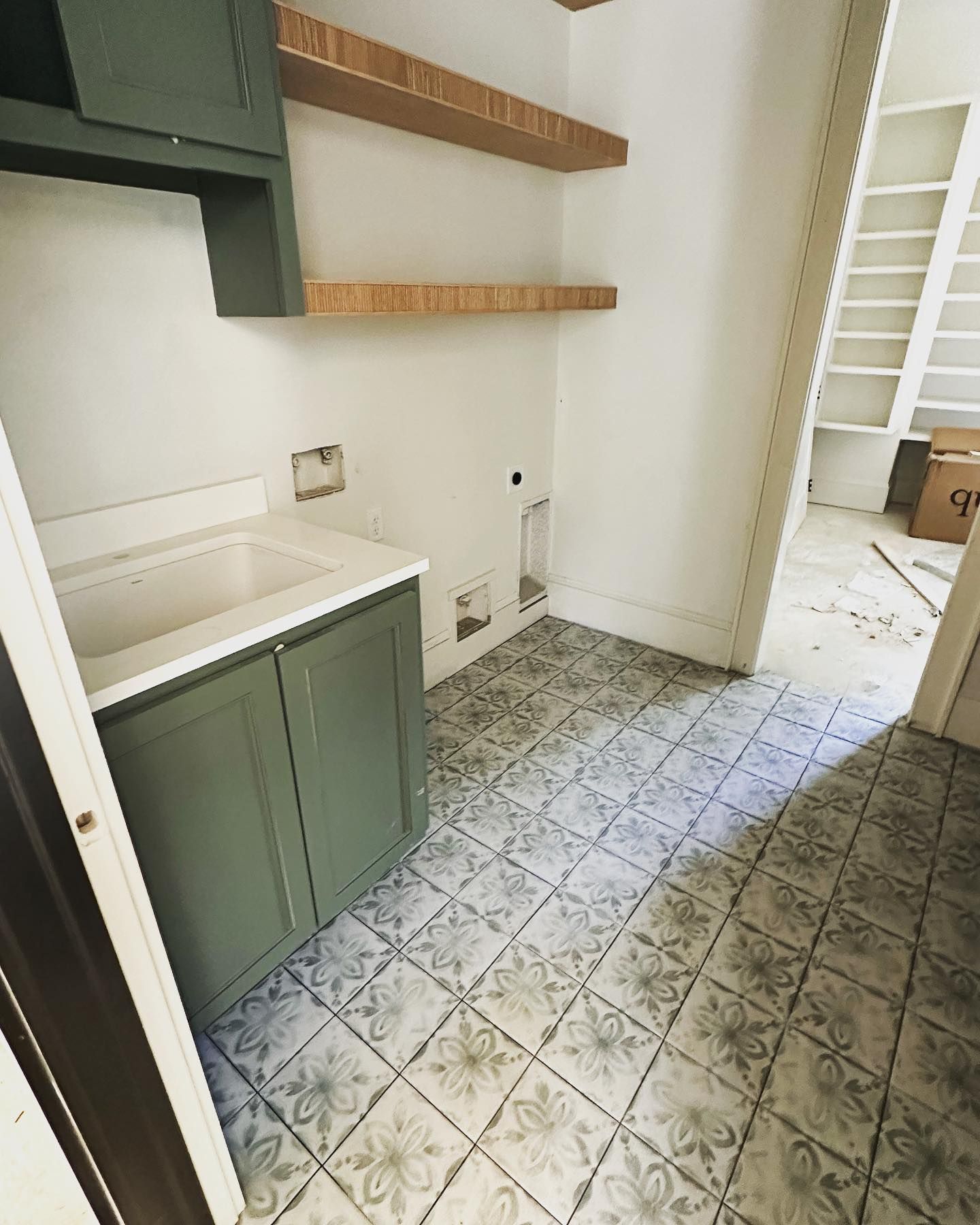 A laundry room with a sink , cabinets , and shelves.