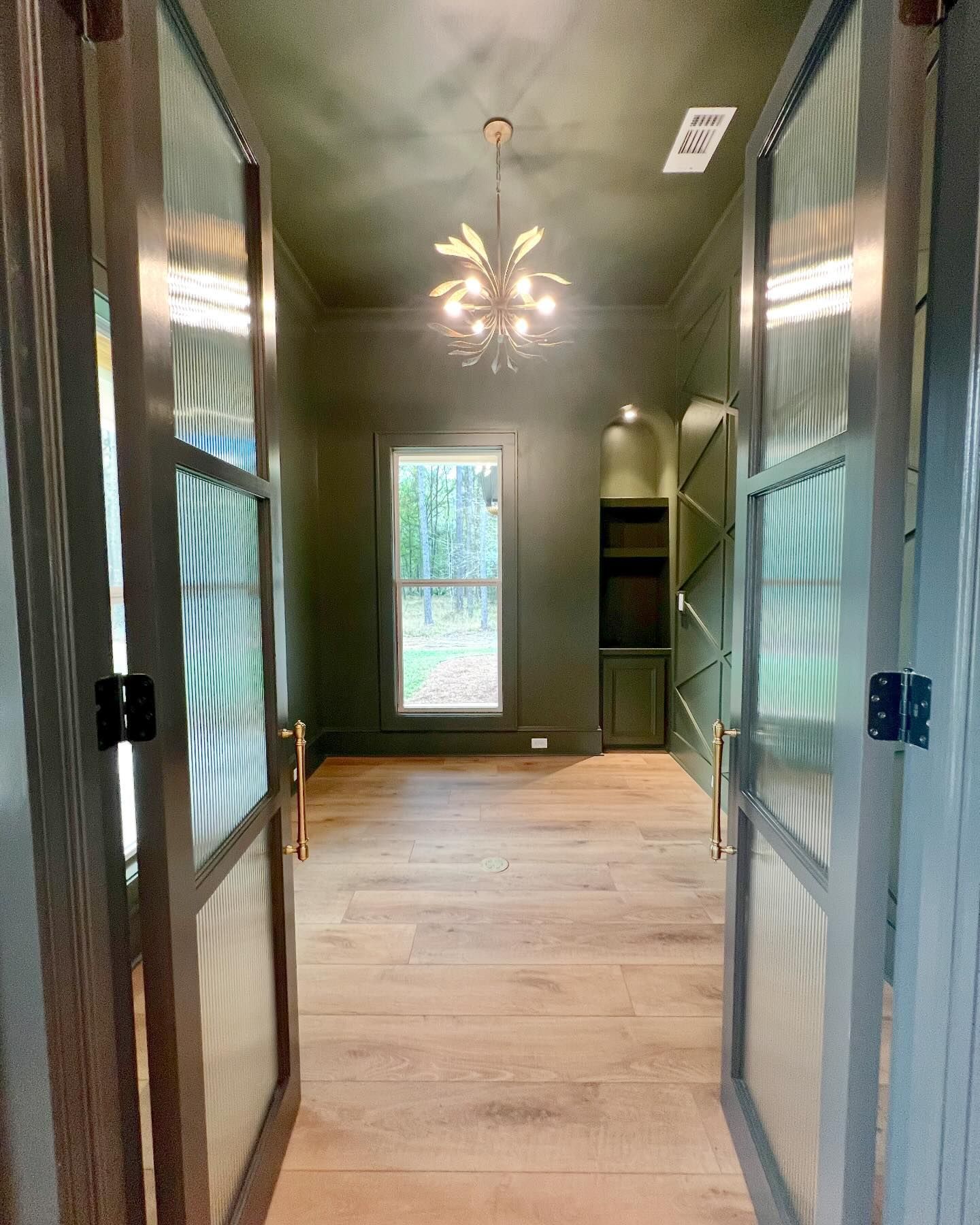 A hallway with a chandelier hanging from the ceiling and a window.