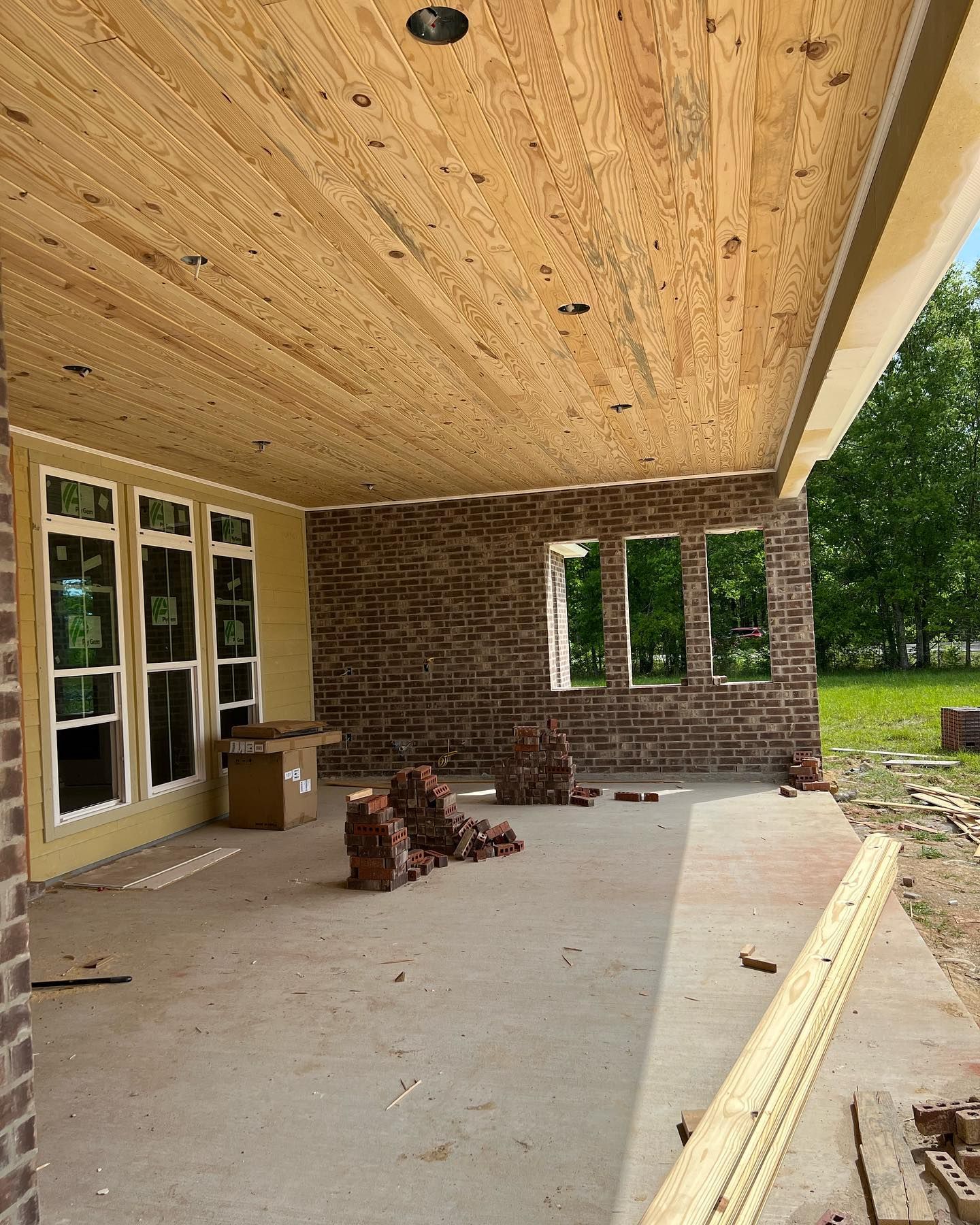 A porch with a wooden ceiling and brick walls under construction.