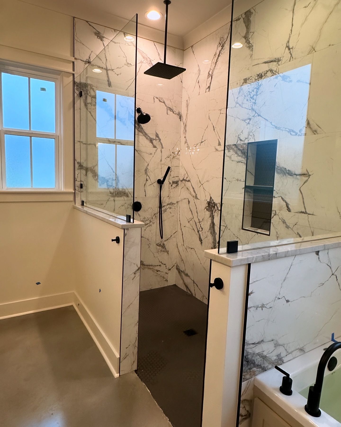 A bathroom with a walk in shower and a tub.