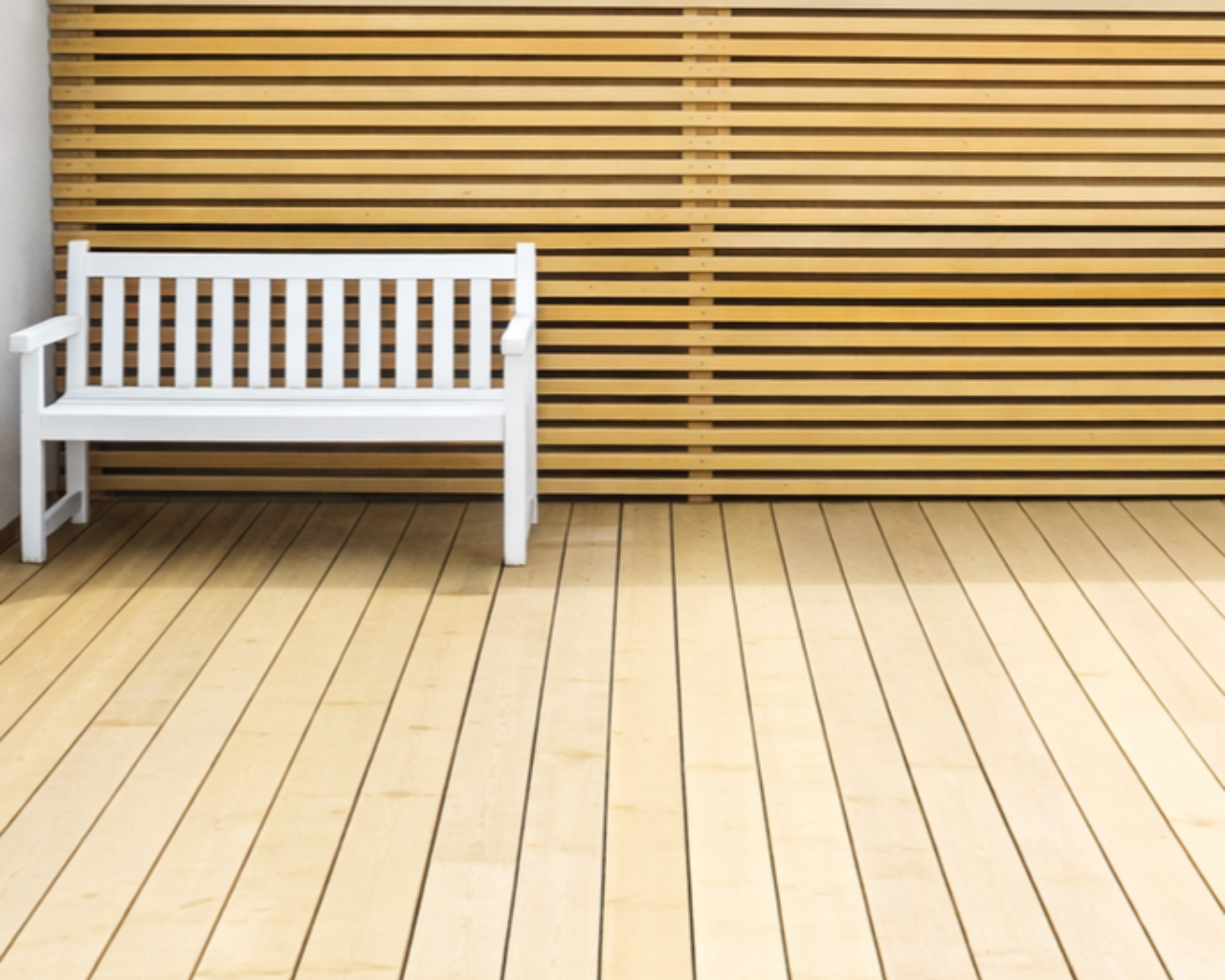 White bench against a horizontal wooden wall and light wood floor.