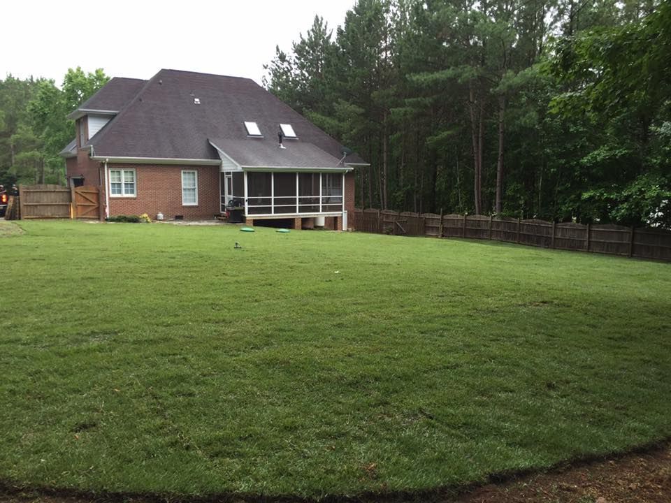 Large brick house with a covered porch beside a broad green lawn and trees in West End, NC.