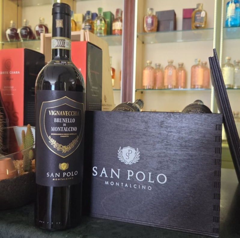 Bottiglia di vino Brunello di Montalcino San Polo accanto alla sua scatola, esposta in un negozio insieme ad altre bottiglie sugli scaffali.