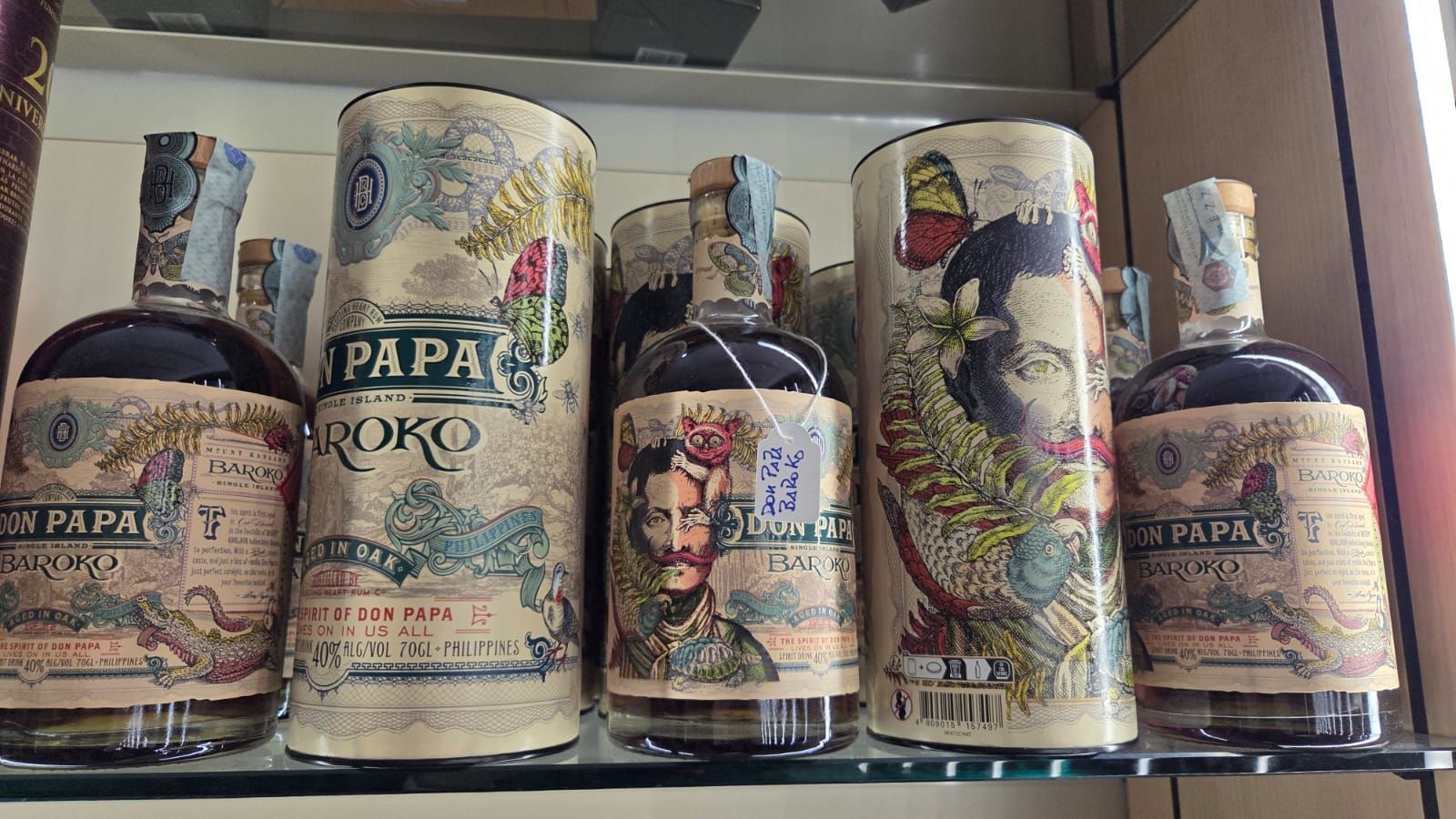Bottiglie di rum Papa Roko su uno scaffale, con etichette di carta decorative e custodie cilindriche.