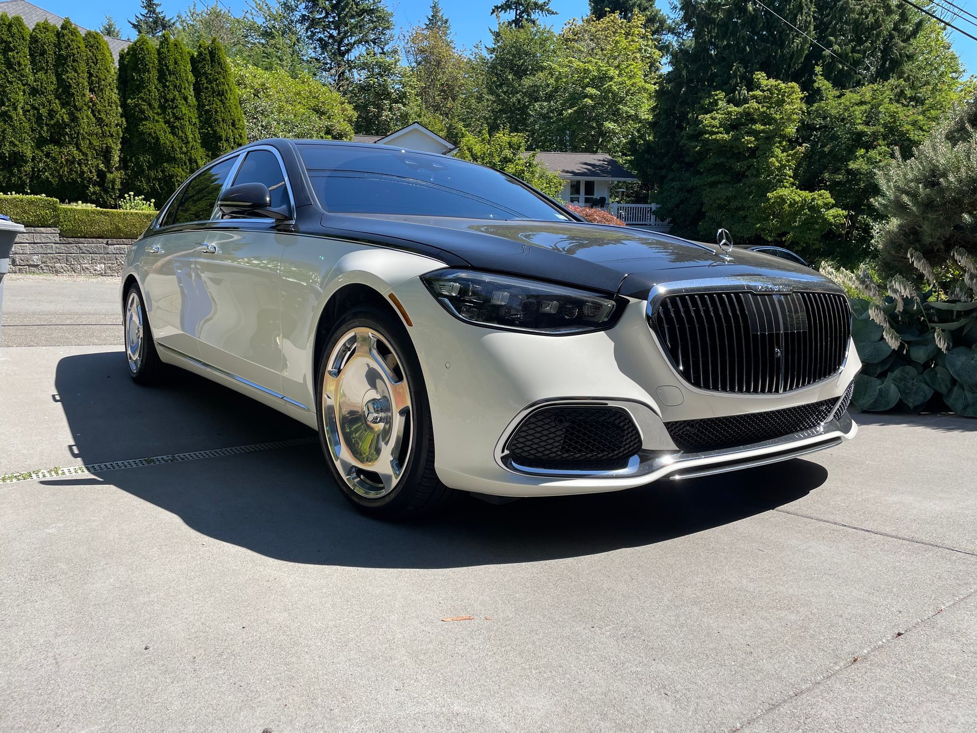 Two-tone white and black Mercedes-Maybach sedan parked on a driveway in front of a house.