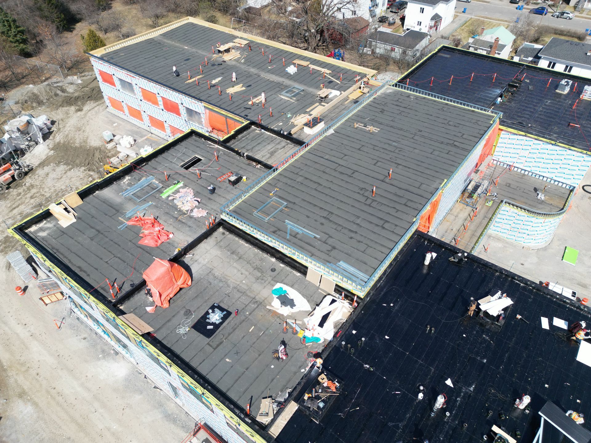 Aerial view of flat-roof buildings with HVAC units, skylights, and patches of snow.