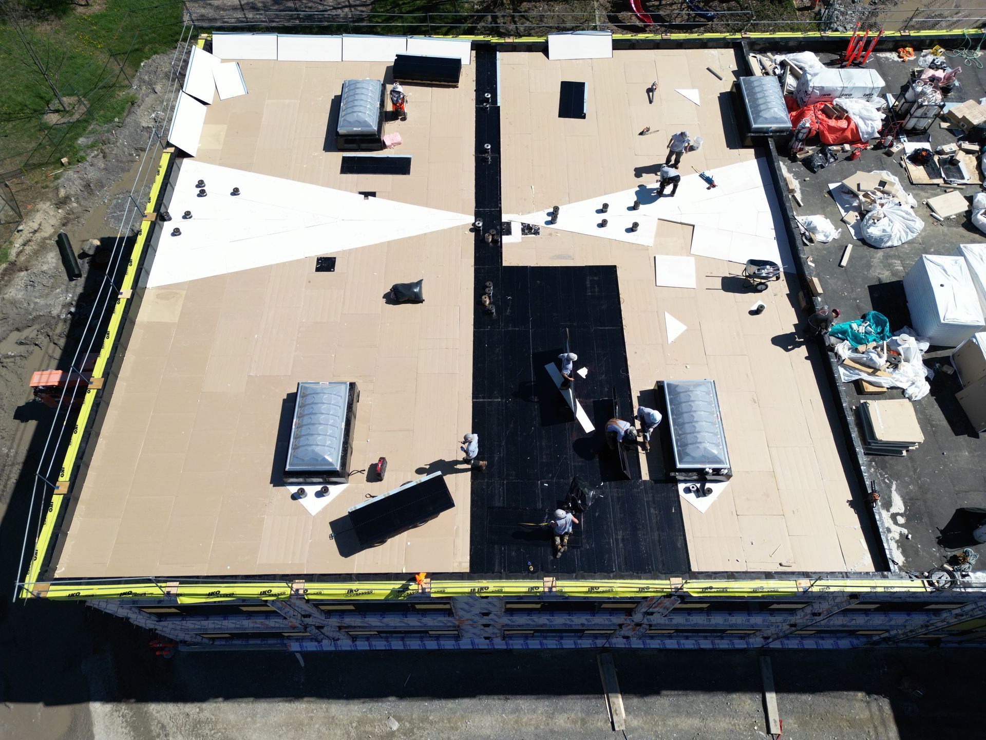 Aerial view of a flat roof with HVAC units and a central black opening under construction