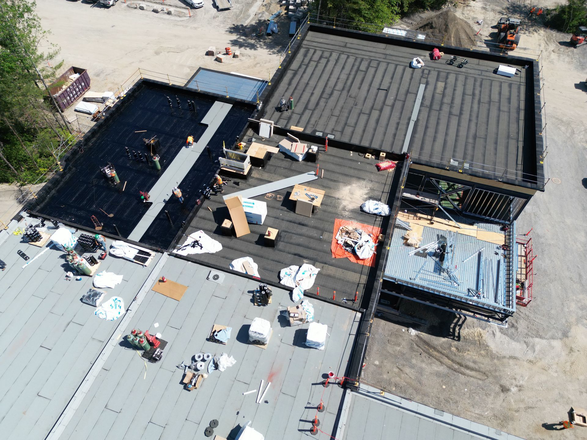 Aerial view of workers repairing a roof with black and gray sections and scattered materials