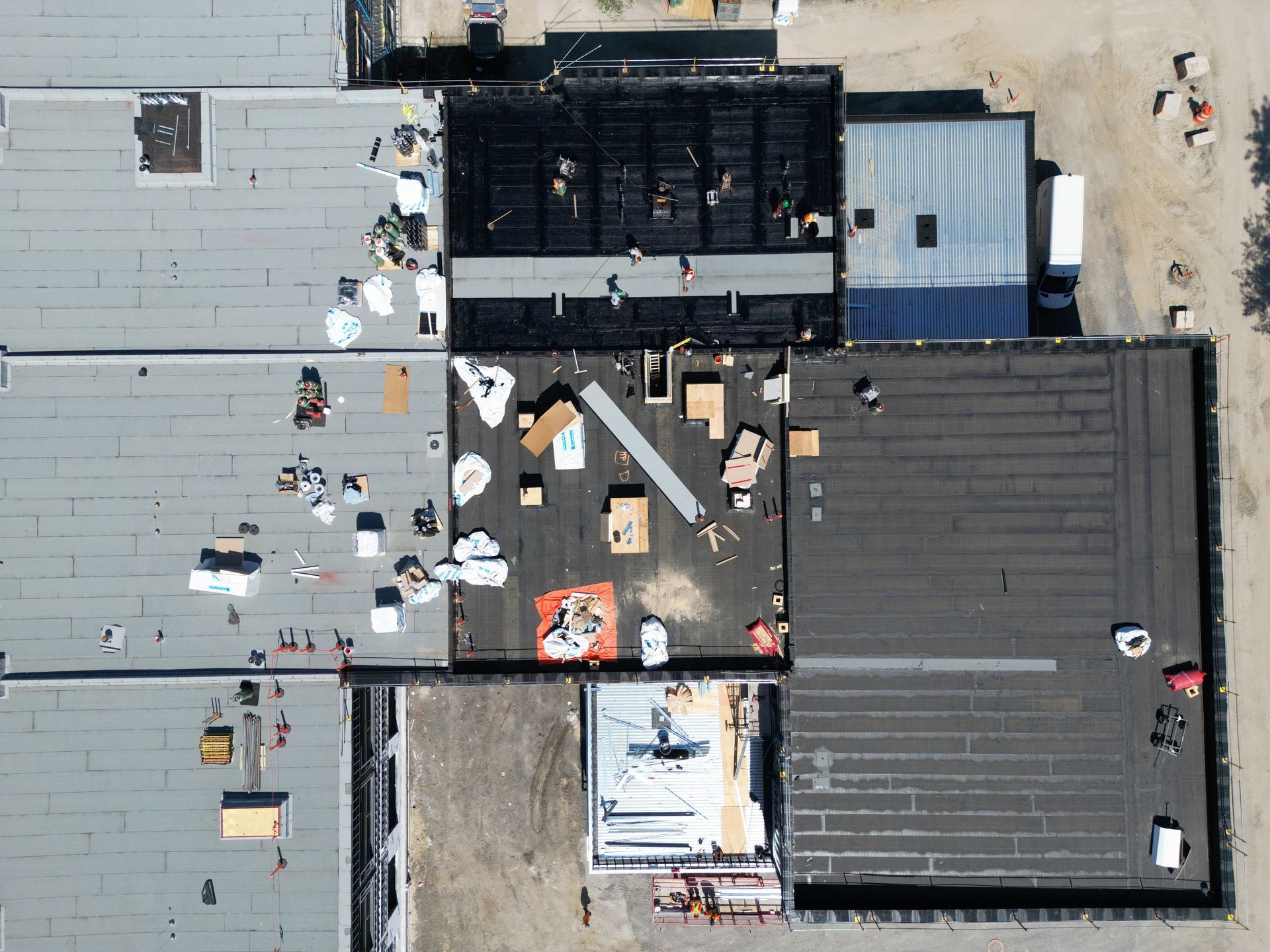 Aerial view of a flat industrial rooftop with HVAC units, vents, and scattered maintenance materials.