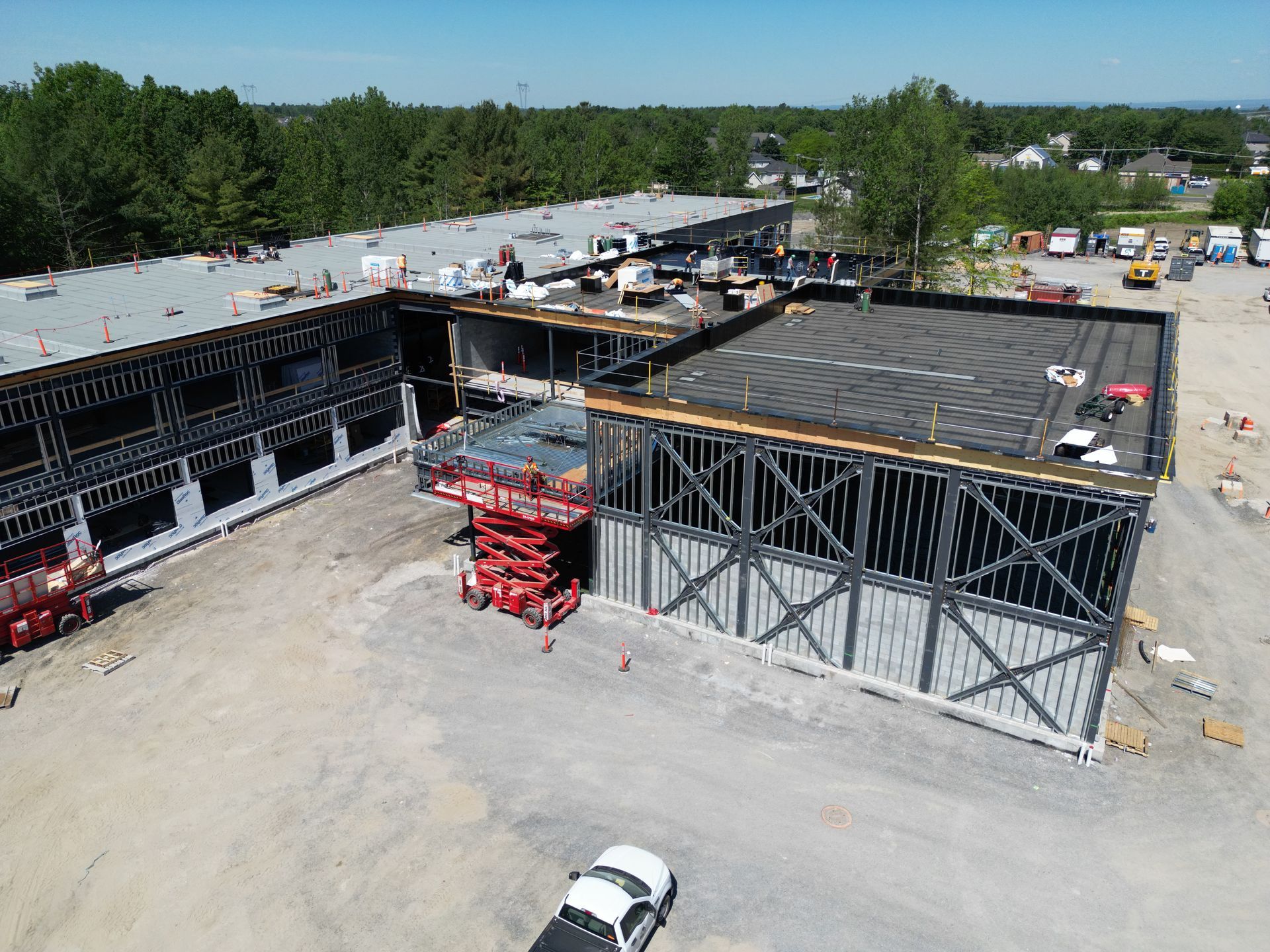 Aerial view of a construction site with steel framing, scaffolding, and a white vehicle in the foreground