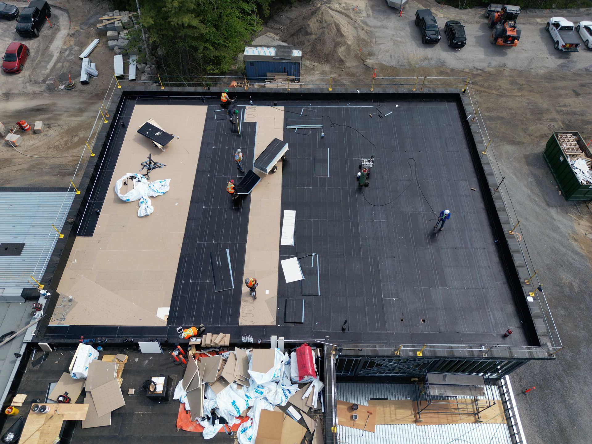 Aerial view of a rooftop with workers and construction materials on a partially repaired building