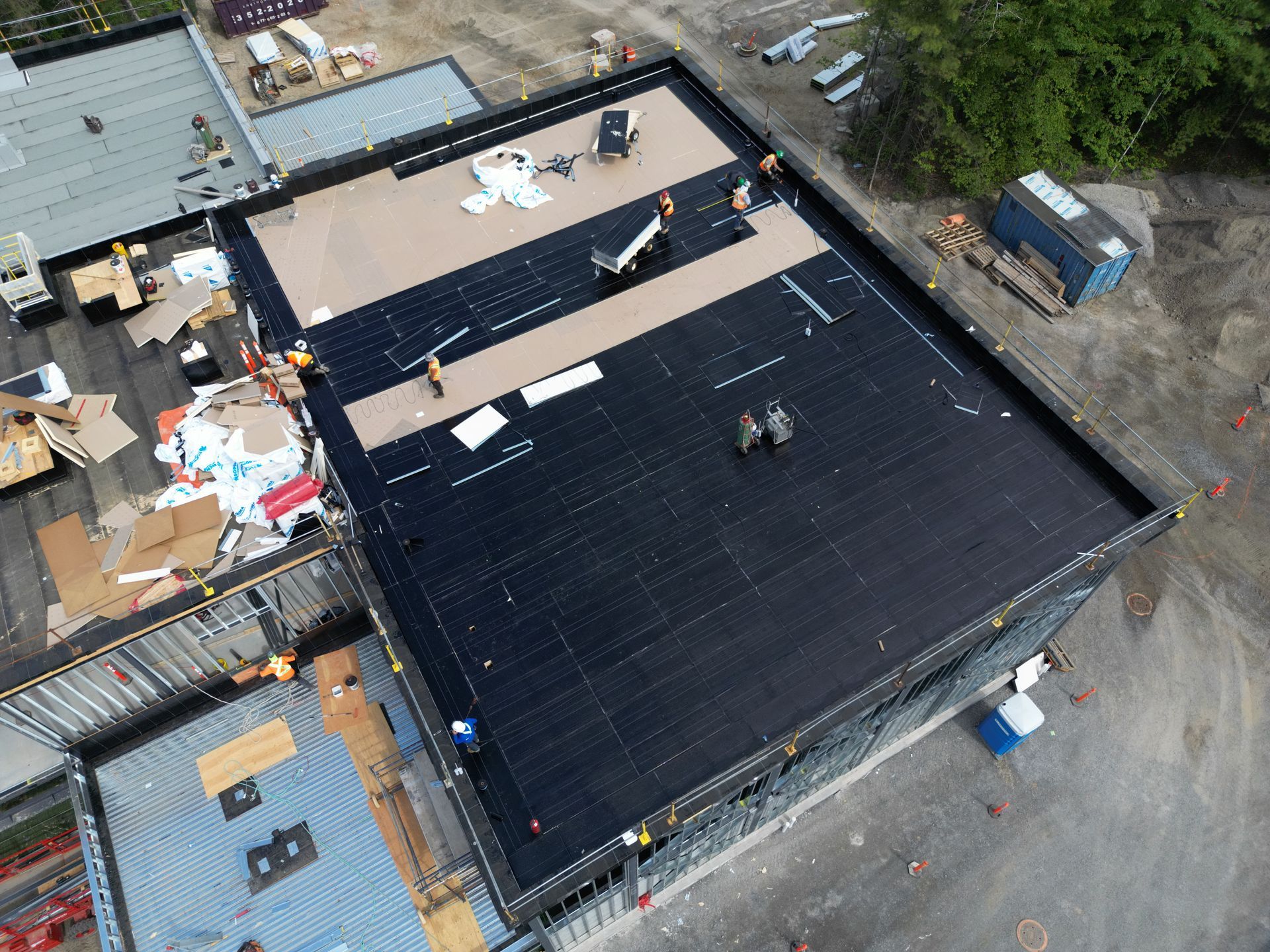 Aerial view of a flat-roofed building under construction with materials scattered around the site.