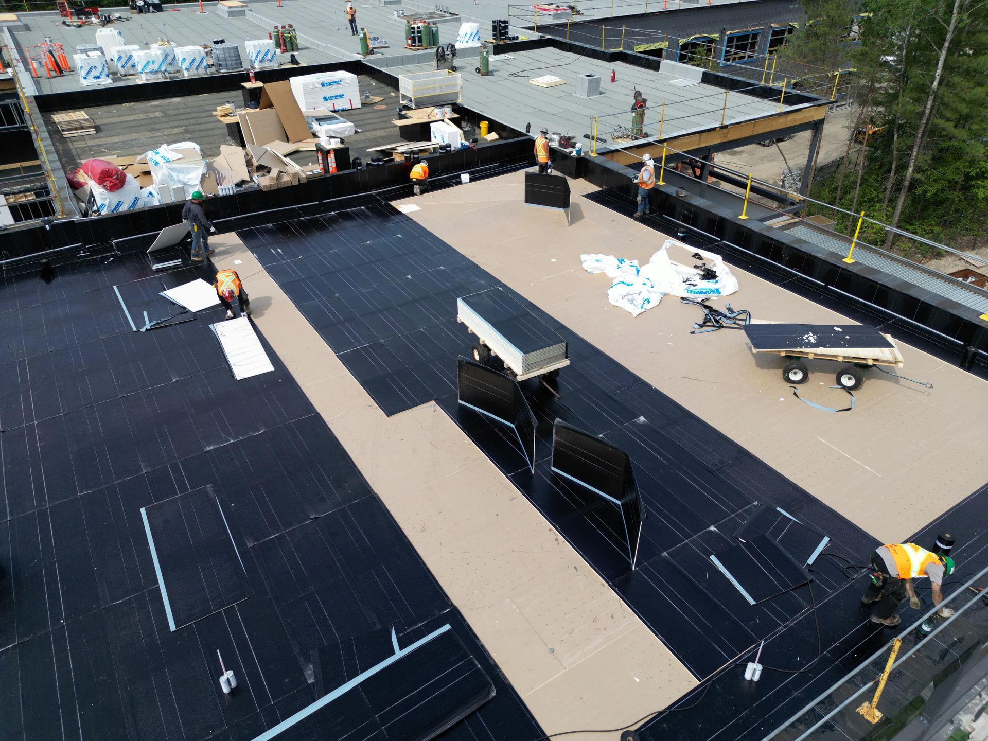 Workers installing black solar panels on a rooftop under construction