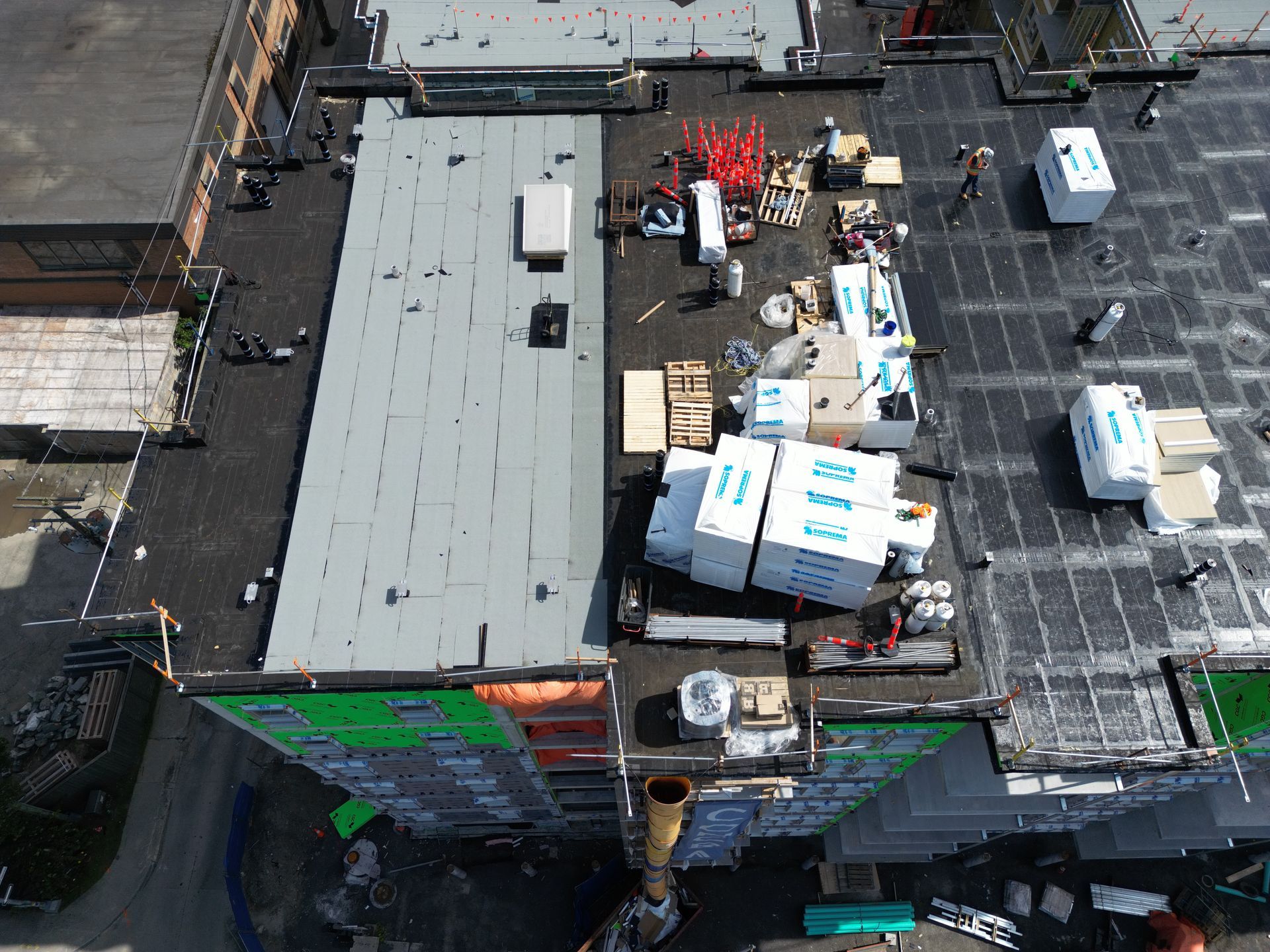 Aerial view of a flat rooftop with HVAC units, materials, and construction supplies grouped near the center.