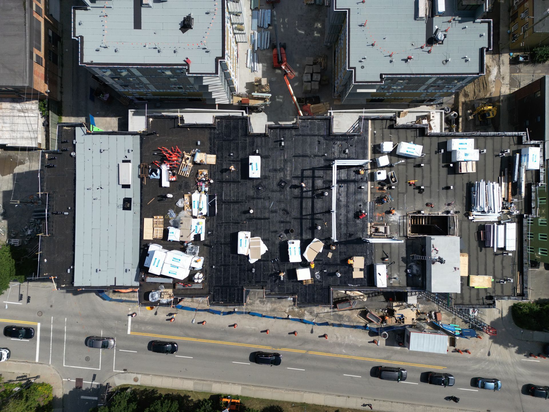 Aerial view of a damaged rooftop with debris and workers beside a busy street