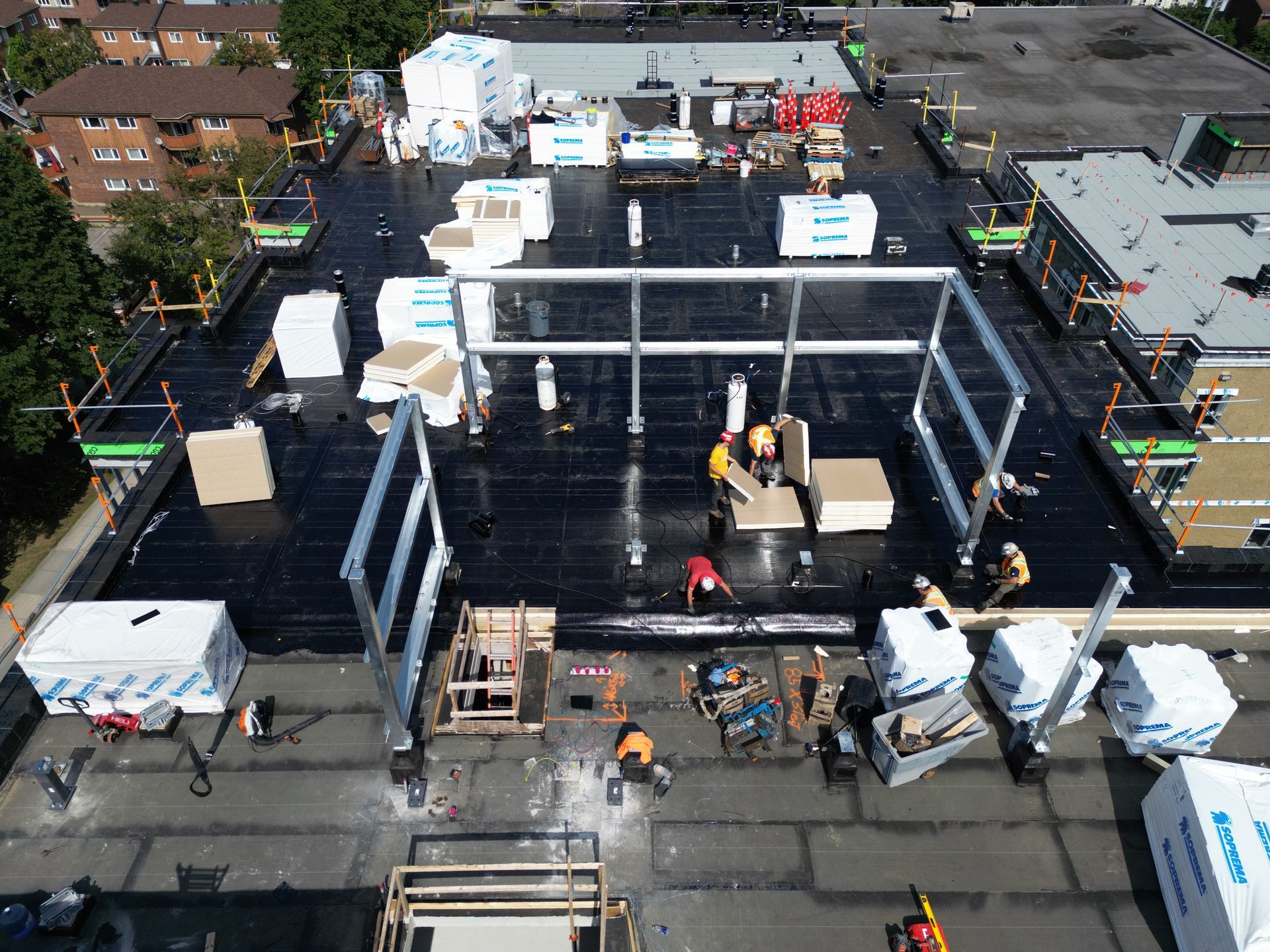 Aerial view of a construction site with workers, scaffolding, and materials surrounding a large building frame