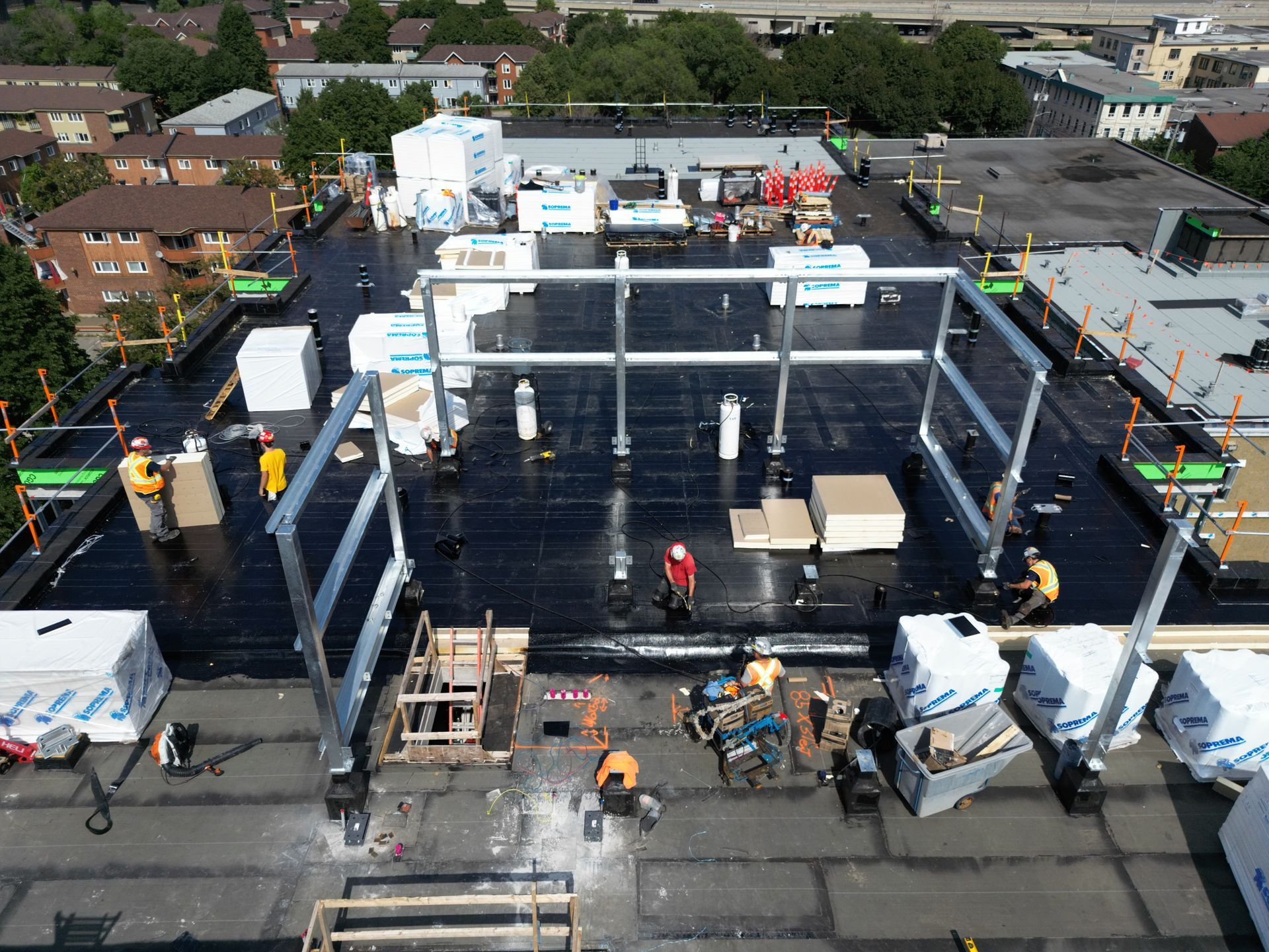 Aerial view of a rooftop construction site with steel frame, workers, and equipment.