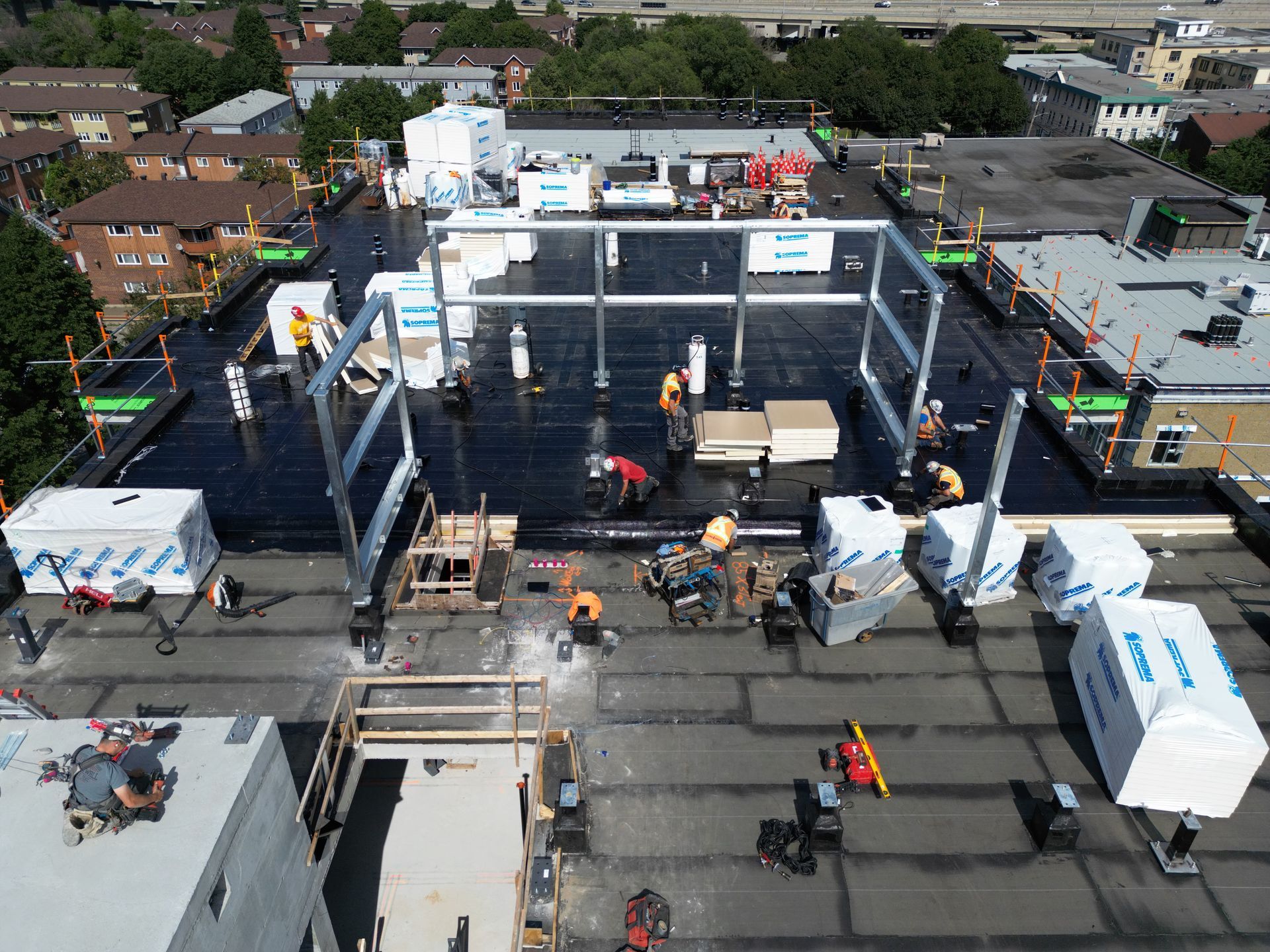 Aerial view of a construction site with workers, scaffolding, and large black wall panels underway.
