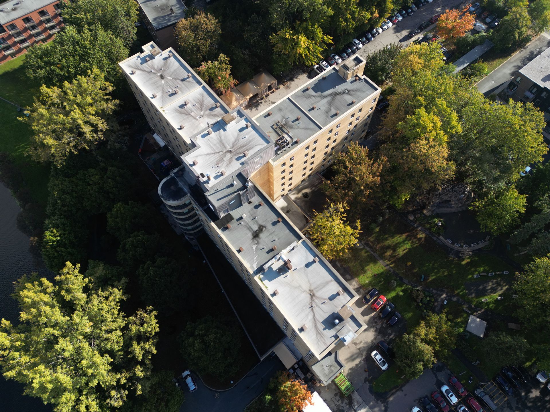 Aerial view of a tan apartment building surrounded by trees and streets.