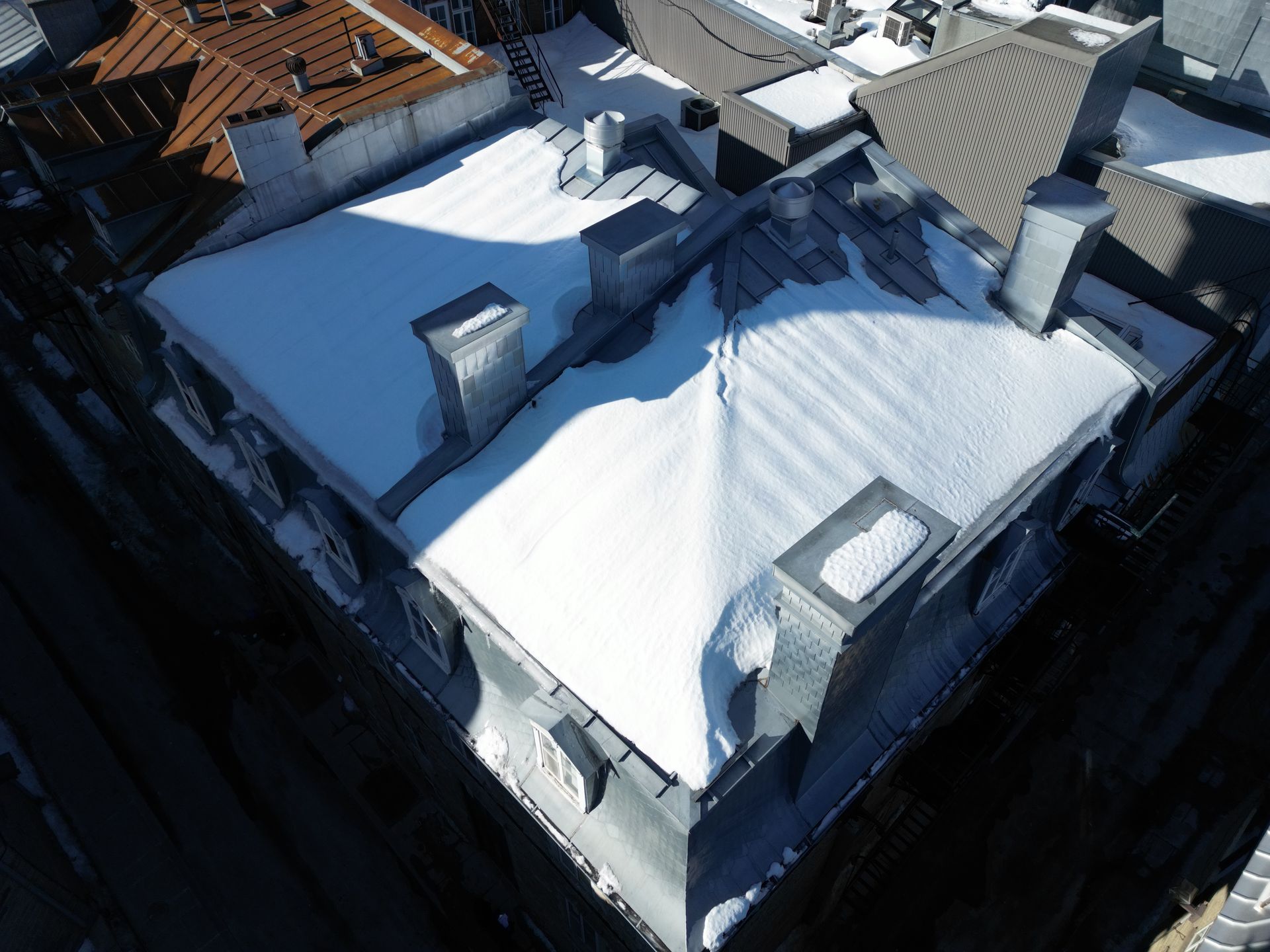 Snow-covered rooftops and chimneys of a house viewed from above