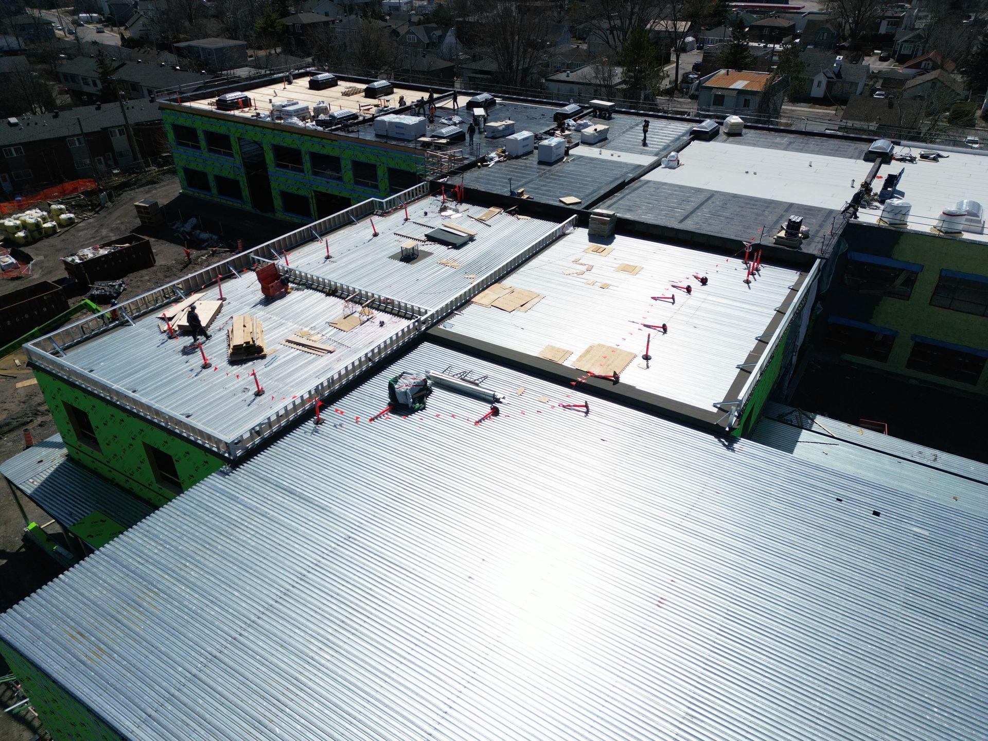 Aerial view of workers on white and green rooftops at a construction site.