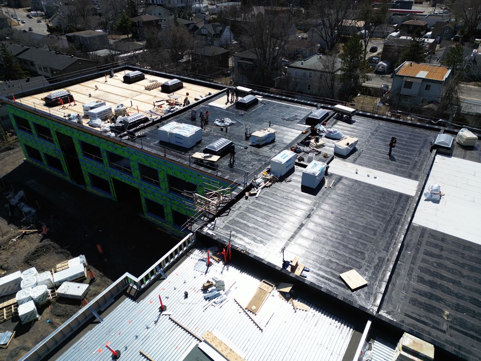 Aerial view of a multi-story building under construction with rooftop equipment and dark solar panels.