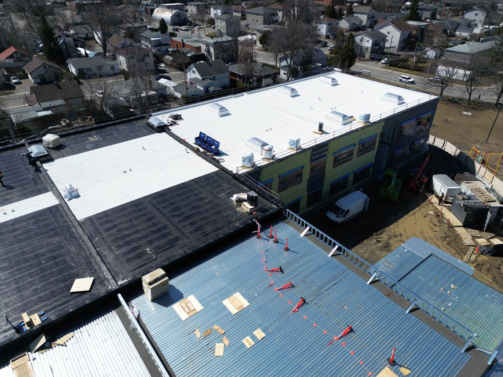 Aerial view of rooftops with workers and materials on a building under construction.