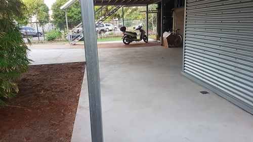 a motorcycle is parked in a driveway under a covered area .