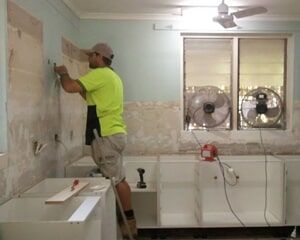 a man is working on a wall in a kitchen .