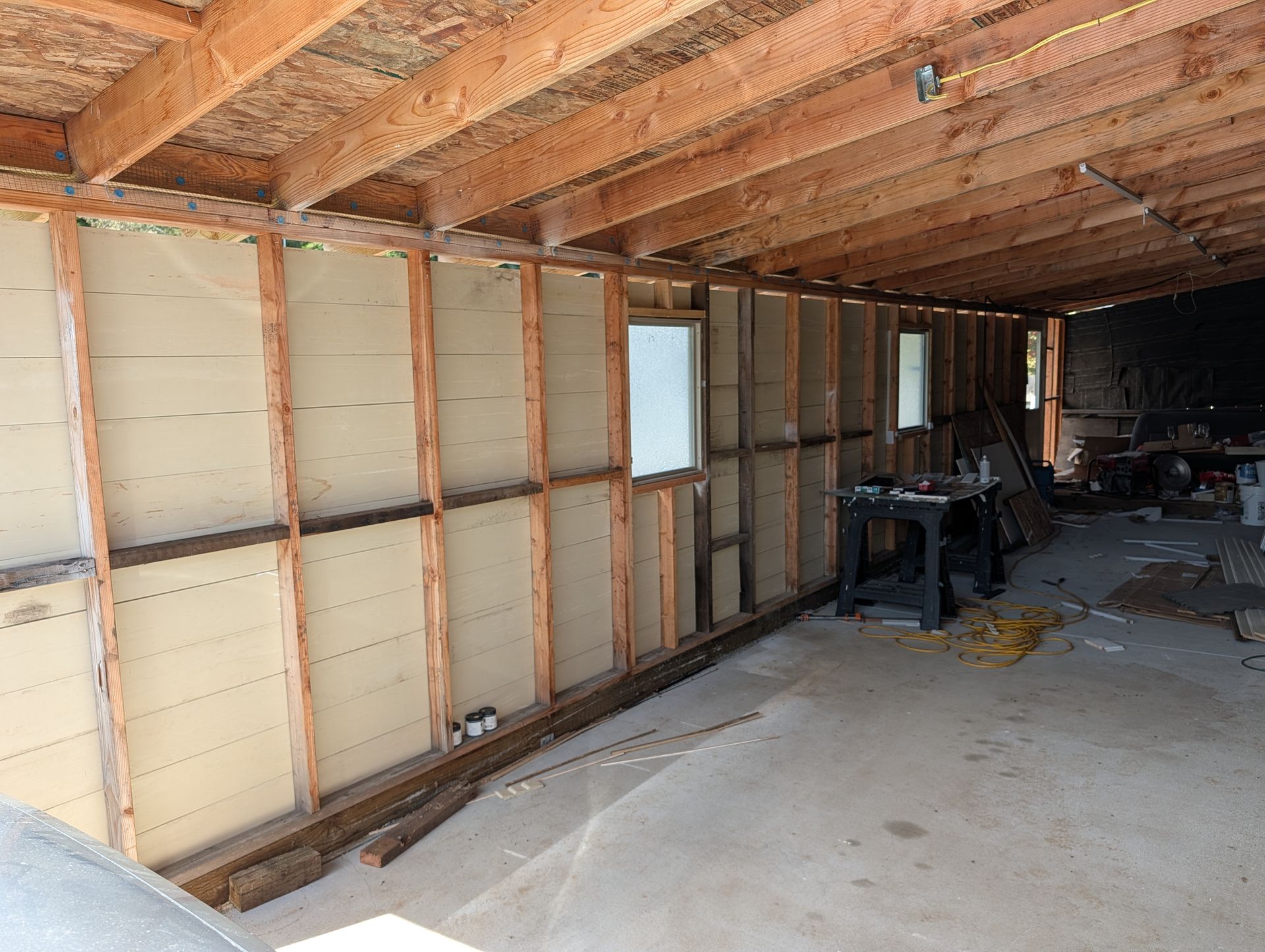 Partially finished basement with exposed wood framing, insulation, and concrete floor