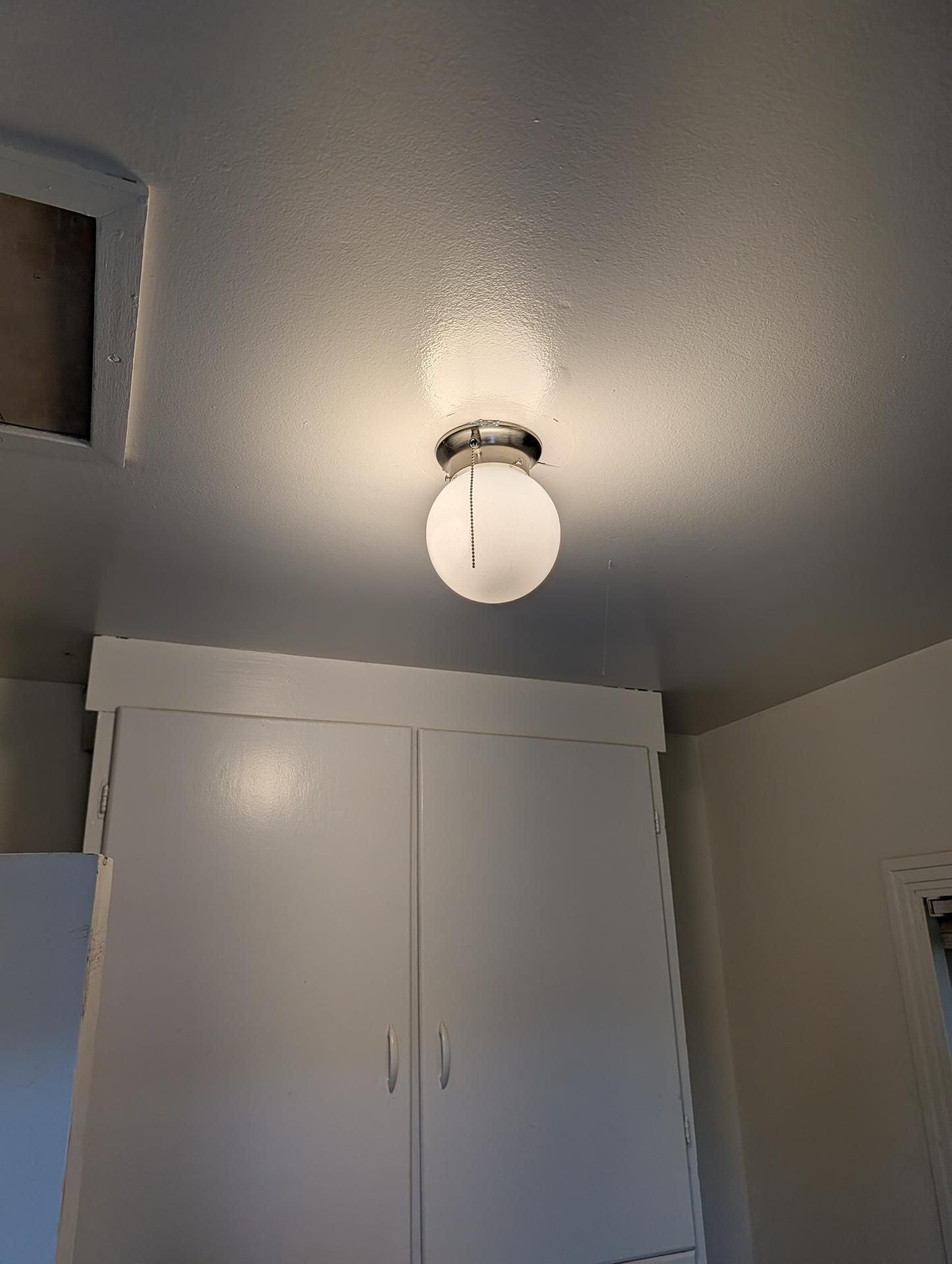 Ceiling light above white closet doors in a small room with gray ceiling and white walls