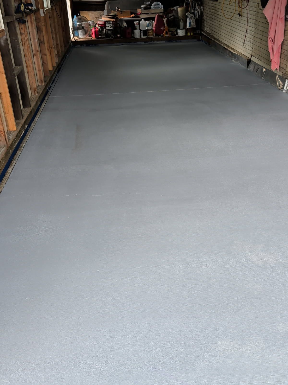 Empty garage with a smooth gray epoxy floor and shelves along the sides