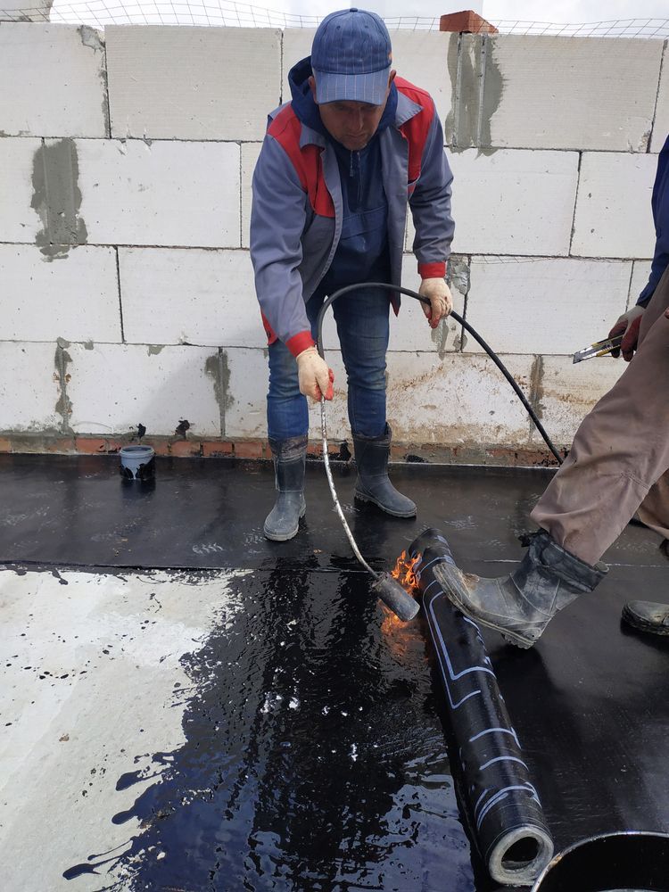 Worker Using a Torch to Melt and Install a Black Roofing Membrane — Consider It Sealed Waterproofing in Cessnock, NSW