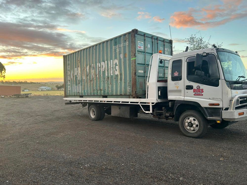 Tow Truck Carrying A Shipping Container In A Parking Lot — Ries Trucking in Gowrie Mountain, QLD