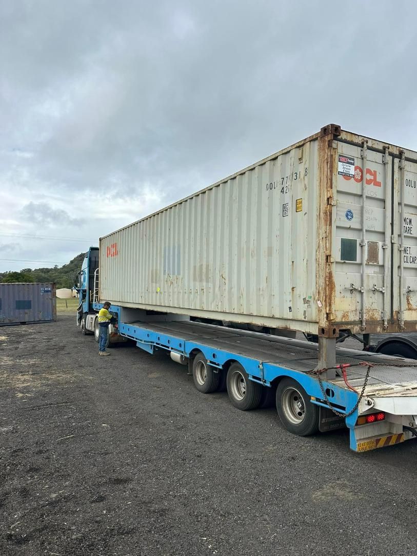 A Semi Truck Is Carrying A Shipping Container On A Trailer — Ries Trucking in Dalby, QLD