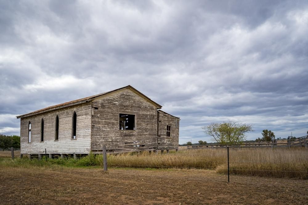 An Old Building In The Middle Of A Field With A Cloudy Sky In The Background — Ries Trucking in Chinchilla, QLD