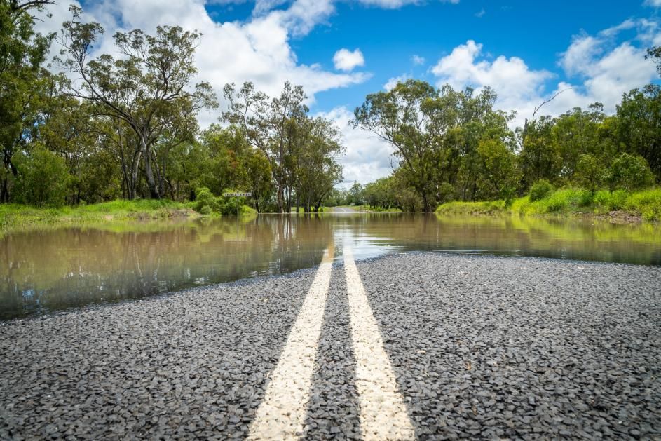 A Flooded Road With Trees On The Side Of It — Ries Trucking in Tara, QLD