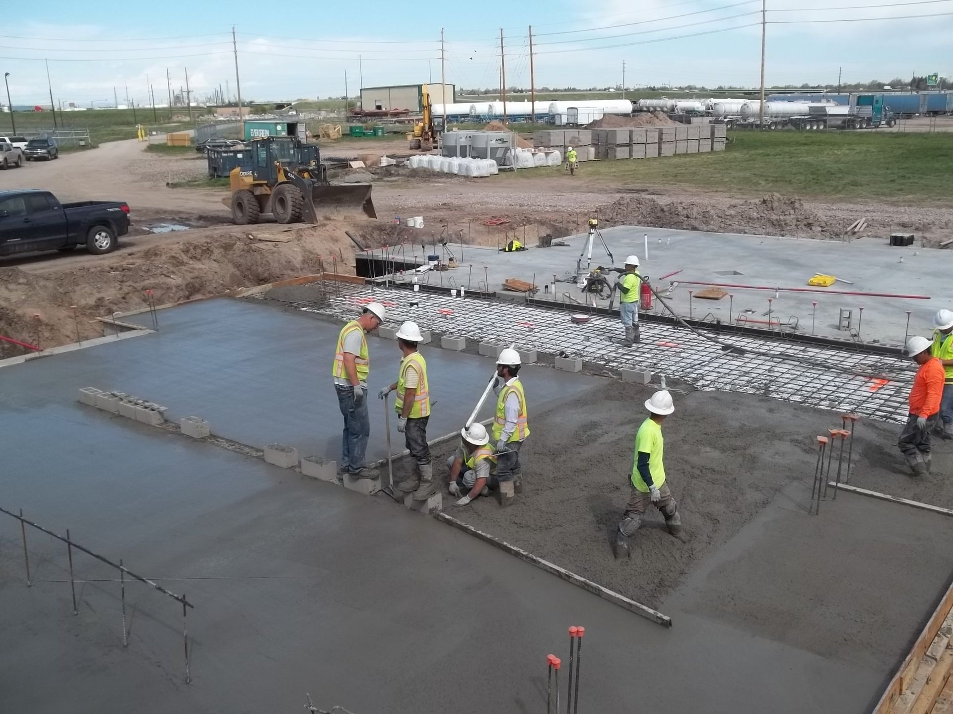 Construction workers pouring and smoothing wet concrete at a large outdoor worksite