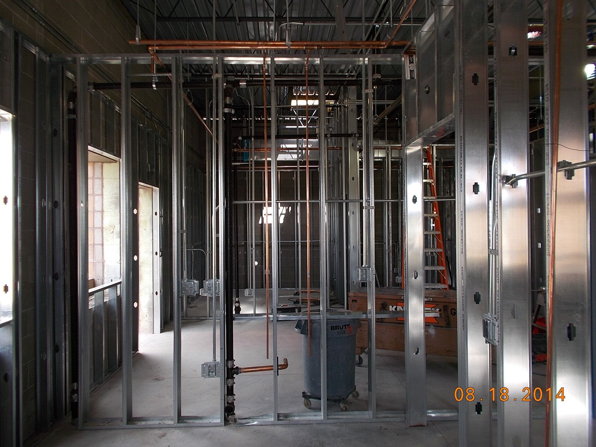 Empty building interior with exposed metal studs, wiring, and construction framing.