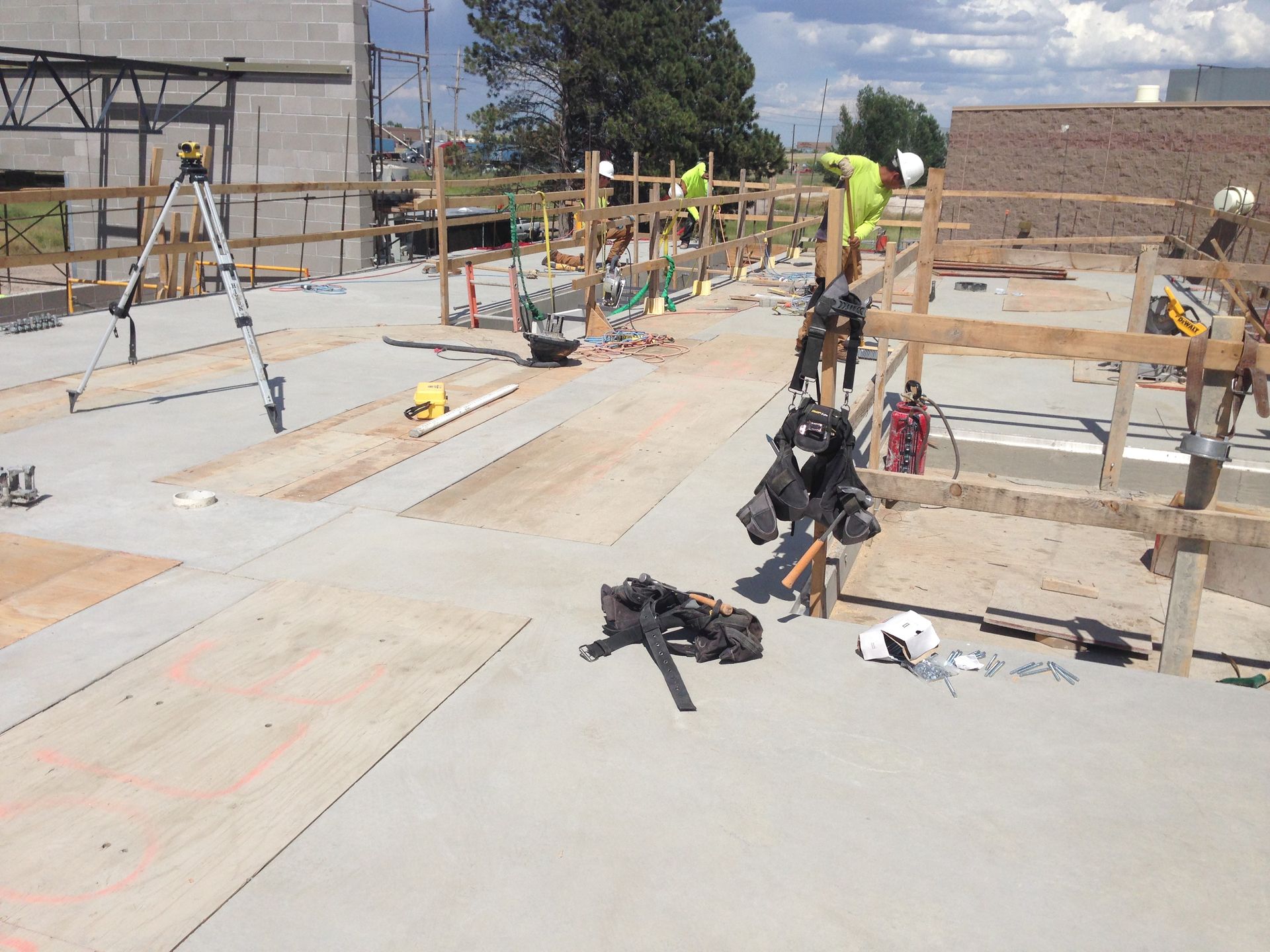 Construction workers pouring concrete on a large foundation slab at an outdoor building site.