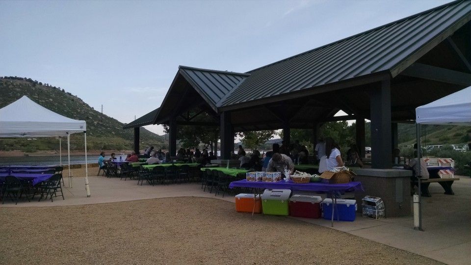 Outdoor pavilion with tables and colorful tablecloths at a community gathering near a hill