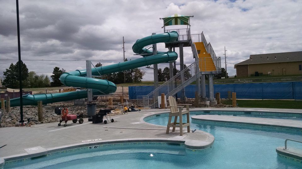 Outdoor pool with teal water slides under a cloudy sky