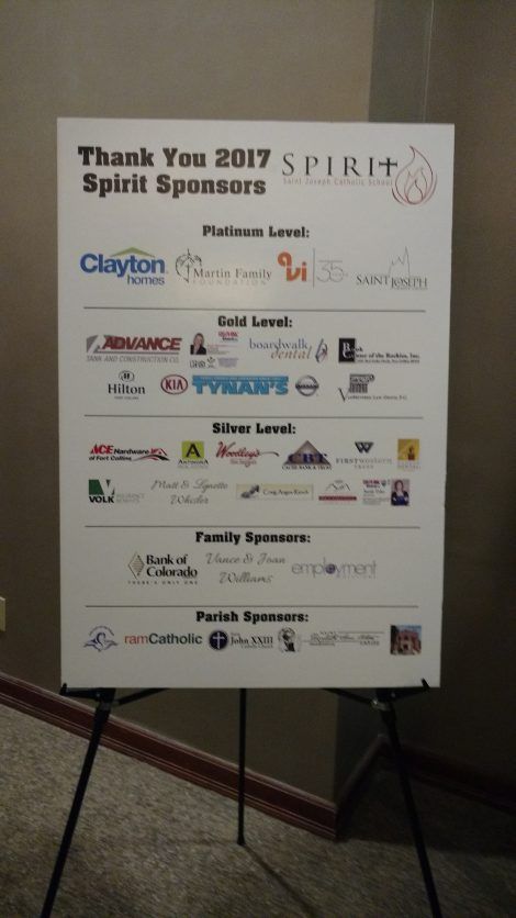 Sponsor signboard at a fundraiser, listing corporate and family sponsors on a white easel poster.