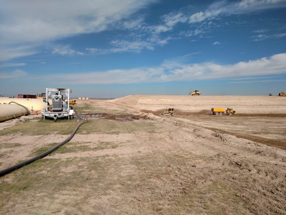 Cloudy sky over a barren, grassy field with a dirt road stretching into the distance