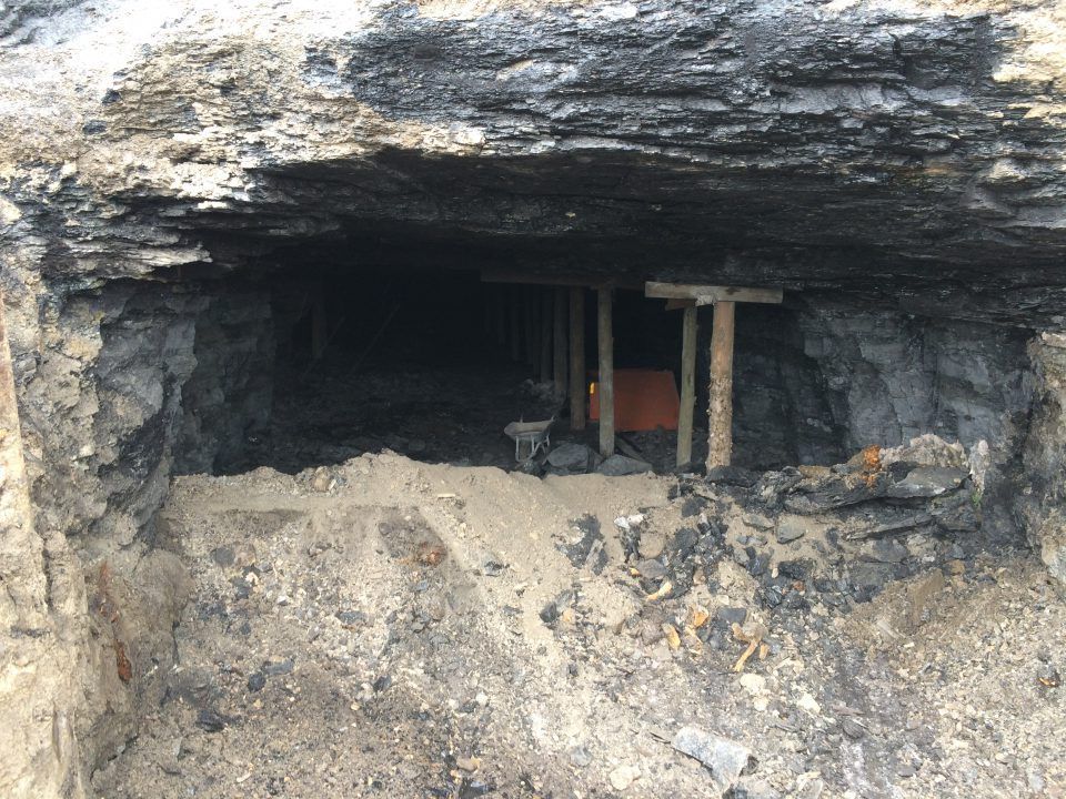 Rock cave entrance with wooden supports and rough dirt floor