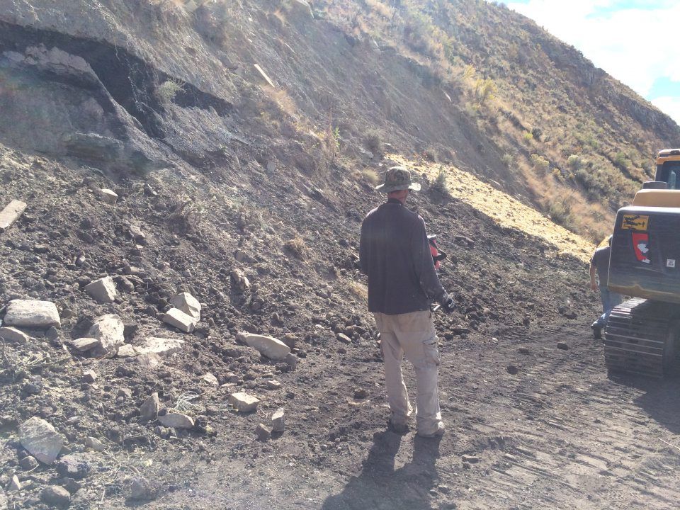 Person standing on a rocky mountain road beside a parked SUV
