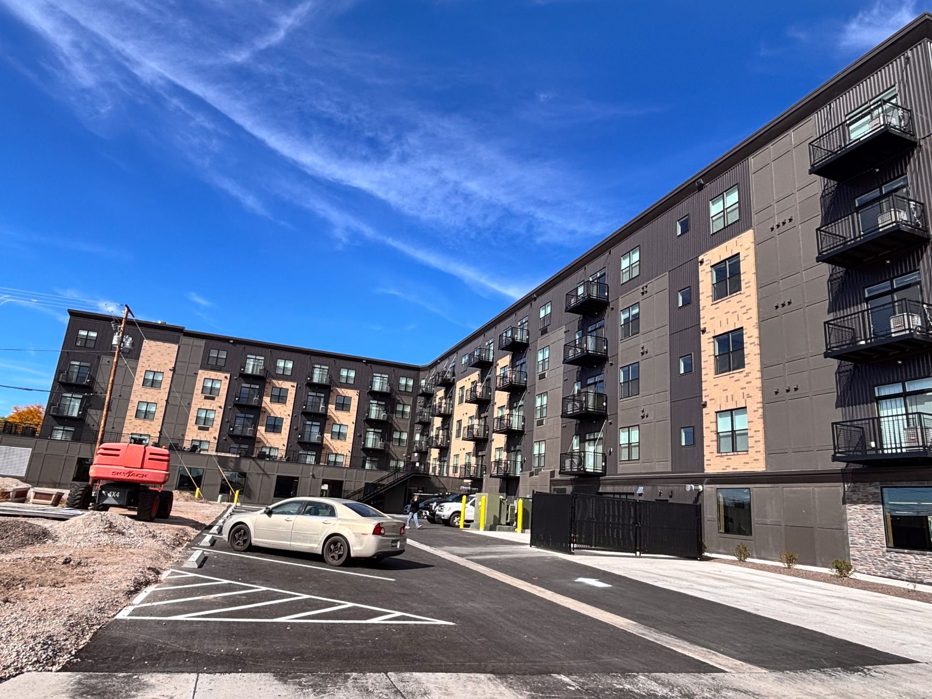 Modern apartment buildings with a parking lot and cars under a bright blue sky