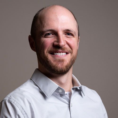 Smiling bald man in a white shirt against a gray background