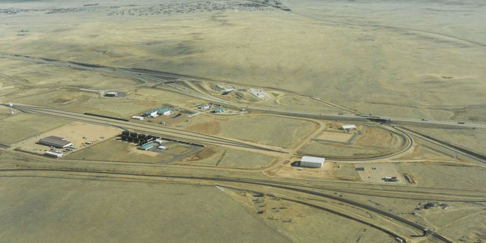 Aerial view of a remote industrial site with roads, buildings, and open desert terrain.