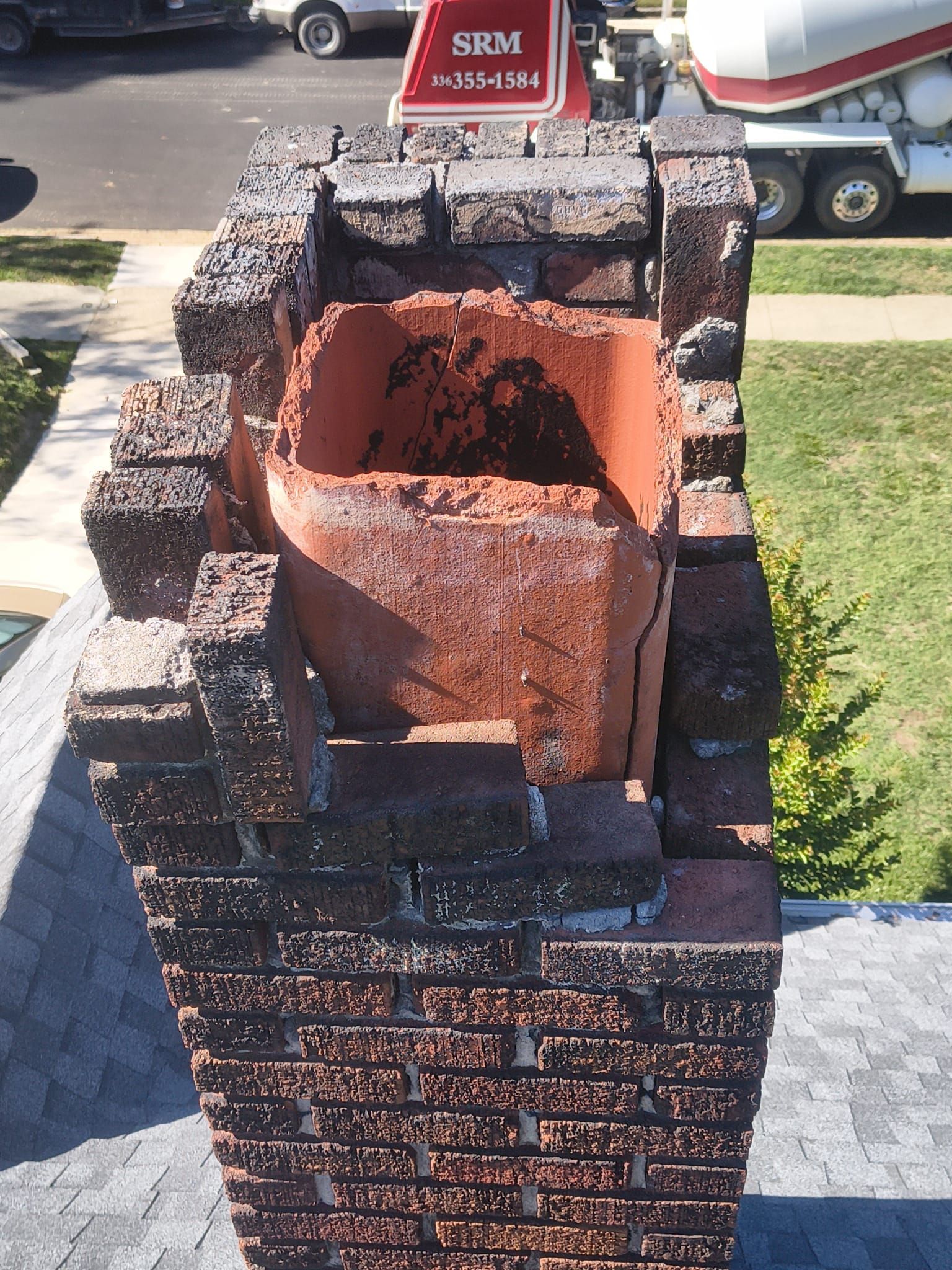 Charred brick fireplace or chimney with a hollow center, standing outdoors on a driveway.